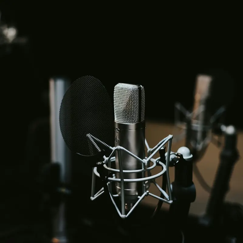 Een studiomicrofoon met popfilter in een donkere opnamestudio.